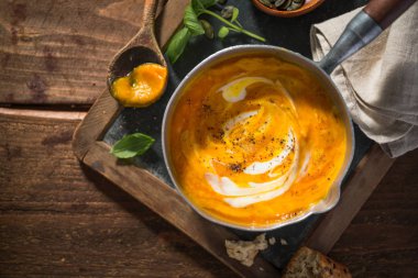 Lezzetli taze balkabağı çorbası ahşap masa üzerinde tencerede pişirilir. Hizmet hazır. Portre. 