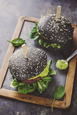 Lezzetli iştah açıcı sağlıklı vegan siyah Burger ahşap masaya servis pancar, quinoa ve avokado sosu ile yüksek açılı görünüş