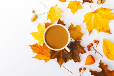 Sonbahar yapraklarının en üst görüntüsü ve beyaz üzerine izole edilmiş bir fincan kahve.