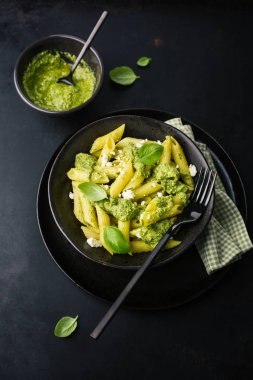 Taze sosu pesto ve peynir ile lezzetli iştah açıcı makarna siyah tablo tabakta servis 