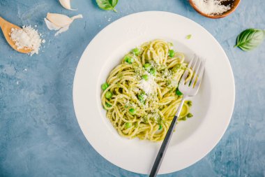 taze sosu pesto, yeşil bezelye ve mavi masada tabakta servis peynir ile lezzetli iştah açıcı Makarna Makarna üstten görünüm