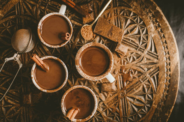 top view of hot chocolate with chocolate chunks in small cups served on dark table