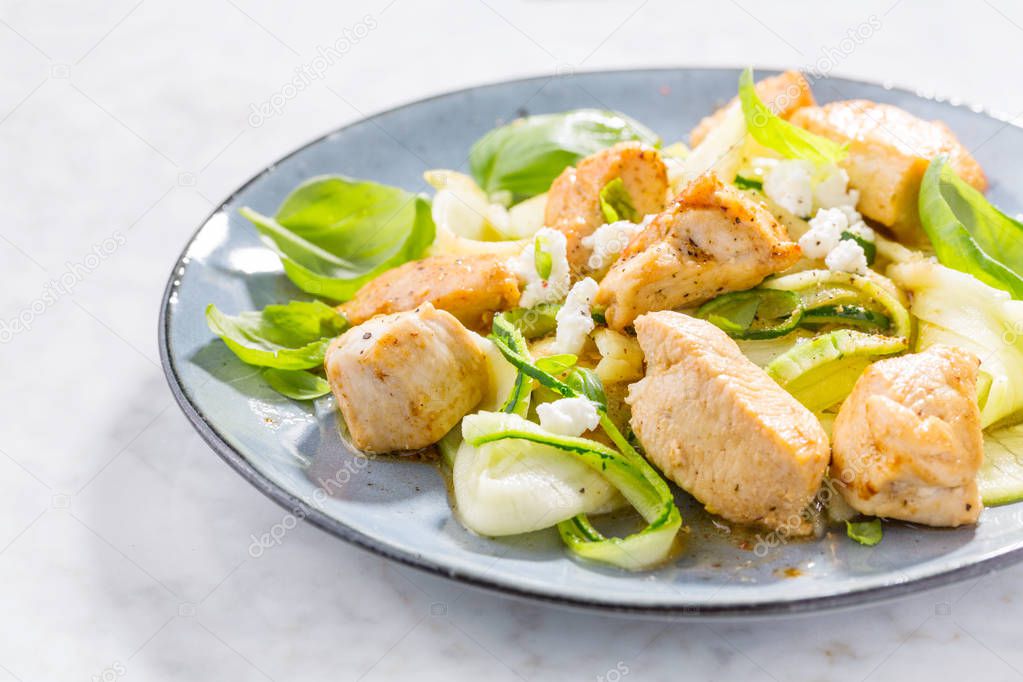 zucchini zoodles noodles with fried chicken chunks and cheese on plate