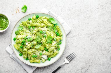 Lezzetli iştah açıcı İtalyan makarna al bronzo pesto sosu, yeşil bezelye, fesleğen ve peynir ile tabakta