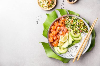 Tasty appetizing poke bowl with salmon, avocado, rice, salad with edamame on grey background clipart