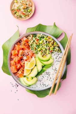 Somon, avokado, pirinç, pembe arka plan üzerinde edamame ile salata ile lezzetli iştah açıcı poke kase