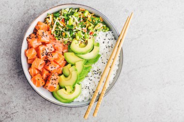 Somon, avokado, pirinç, edamame gri arka plan üzerinde salatası ile lezzetli iştah açıcı poke kase