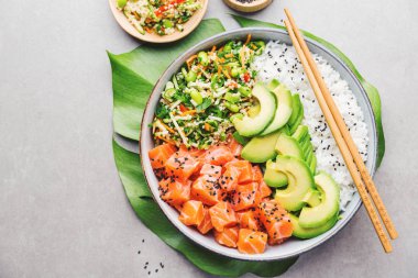 Somon, avokado, pirinç, edamame gri arka plan üzerinde salatası ile lezzetli iştah açıcı poke kase