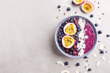 Lezzetli iştah açıcı smoothie acai kase kesilmiş tutku meyve, hindistan cevizi gevreği ve gri arka plan üzerinde kakao uçları ile dekore yabani çilek, yapılan