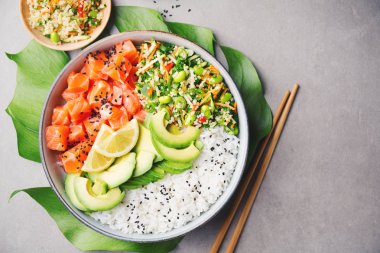 Somon, avokado, pirinç, edamame gri arka plan üzerinde salatası ile lezzetli iştah açıcı poke kase