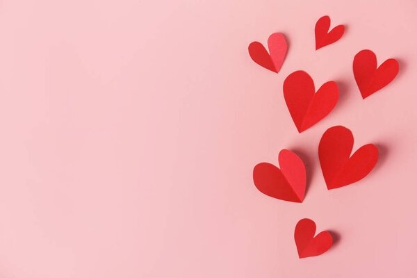 valentines red paper hearts on pink background