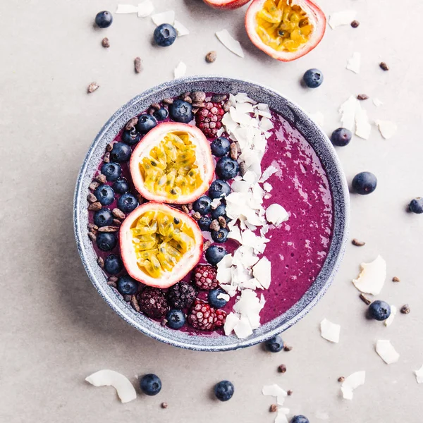 Lezzetli iştah açıcı smoothie acai kase kesilmiş tutku meyve, hindistan cevizi gevreği ve gri arka plan üzerinde kakao uçları ile dekore yabani çilek, yapılan