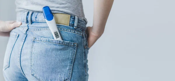 closeup of girl with positive pregnancy test with two stripes in jeans pocket