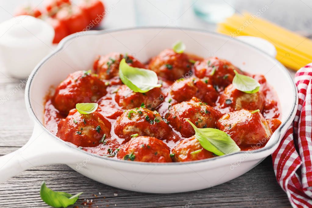 Homemade meatballs with tomato sauce and spices served in pan on grey background