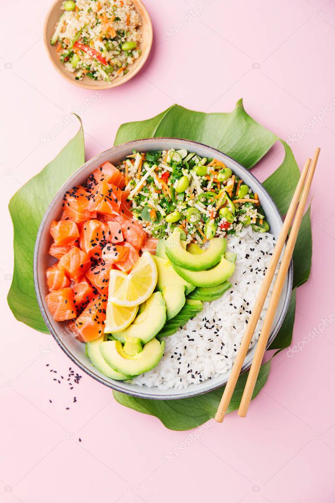 Tasty appetizing poke bowl with salmon, avocado, rice, salad with edamame on pink background