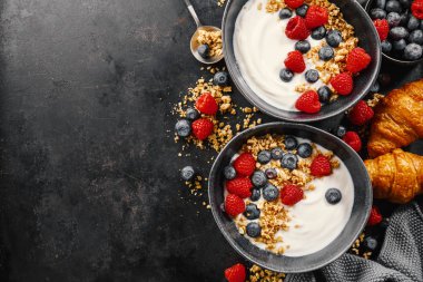 Lezzetli taze yoğurt, granola ve meyve kase kahvaltı. Koyu arka plan. Portre. 