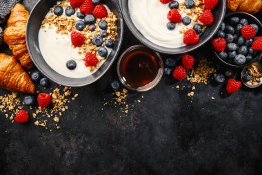 Lezzetli taze yoğurt, granola ve meyve kase kahvaltı. Koyu arka plan. Portre. 