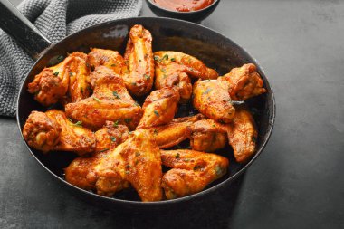 Lezzetli tavuk kanadı pişmiş veya ızgara tava servis sos. Koyu arka plan. Portre. 