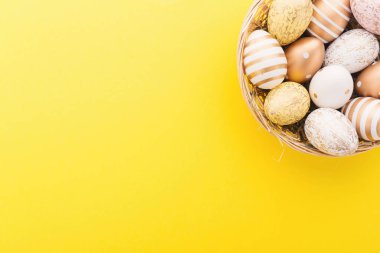 Düz yatıyordu, altın yumurta yuvada Sarı zemin üzerine. Paskalya arka plan veya Paskalya kavramı. Yatay.