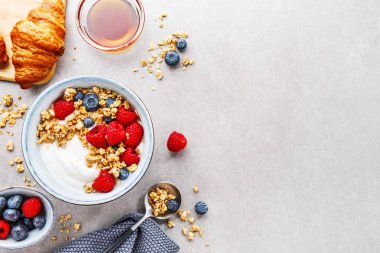 Lezzetli taze yoğurt, granola ve meyve kase kahvaltı. Gri arka plan. Portre. Üstten Görünüm. 