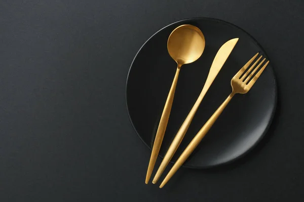 Gold cutlery set on black background — Stock Photo, Image