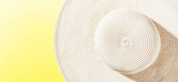Straw hat on bright yellow sunny background