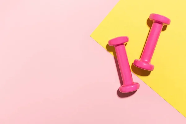 Kurzhanteln flach auf rosa und gelb — Stockfoto