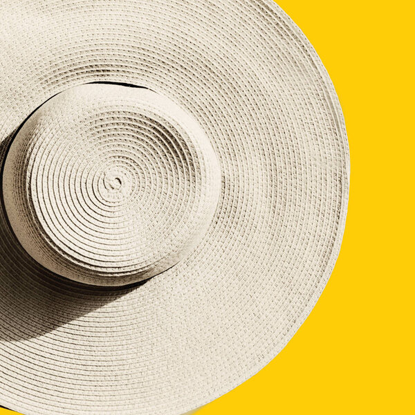 Straw hat on bright yellow sunny background