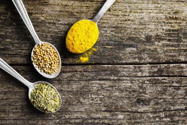 Ahşap arka planda kaşıklardaki baharatlar