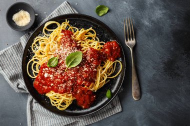 Koyu arkaplanda servis edilen domates soslu lezzetli spagetti makarnası.. 