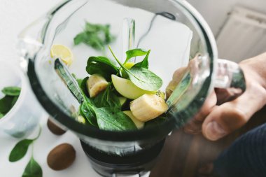 Adam blender 'da yeşil smoothie pişiriyor. Yakın çekim.