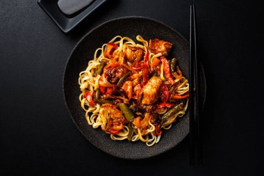 Sebzeli ve soslu Asya eriştesi. Koyu arkaplan.  