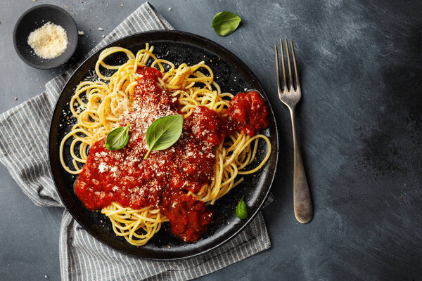 Tasty appetizing spaghetti pasta with tomato sauce served on plate on dark background. 