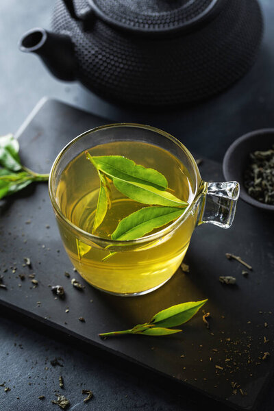 Closeup of brewed green tea in cup served on plate on table. 