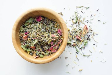 Kuru dağ bitki çayı ahşap bir kabın içinde karıştırın ve beyaz arka plan üzerinde dağınık