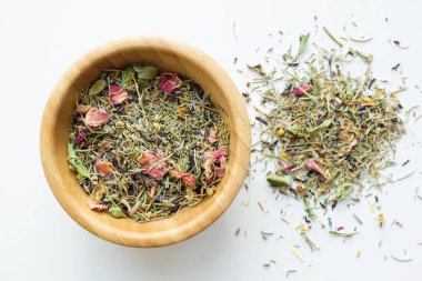 Kuru dağ bitkisel çay karışımı ahşap bir kase içinde beyaz arka plan, üstten görünüm