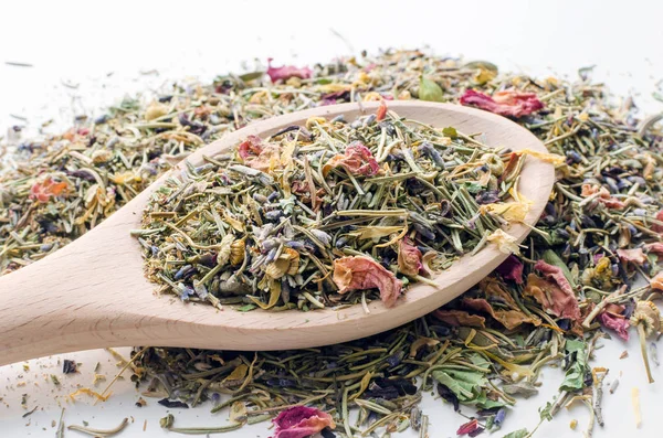 dry mountain herbal tea mix in a big wooden spoon over white background