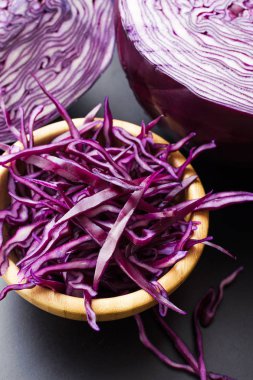 Koyu gri arka plan üzerinde kırmızı lahana salatası ahşap kase yarım lahana baş rendelenmiş