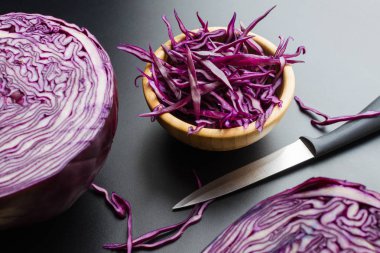 kırmızı lahana salatası yarım lahana kafa ve bıçak, koyu gri arka plan ahşap kase kıyılmış