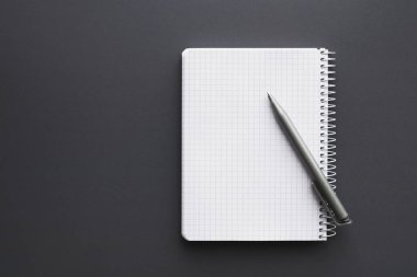Boş beyaz defter kalem ile gri ofis masası üzerinde açıldı. Üstten görünüm, kopya alanı.