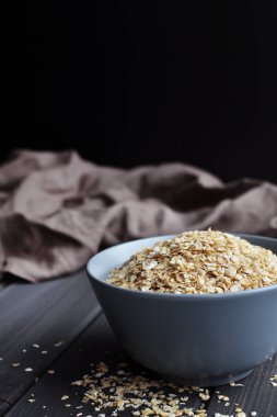 Koyu ahşap arka plan üzerinde seramik kase yulaf, kopyalama alanı