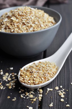 Seramik kase ve doku ile koyu ahşap masa kaşık haddelenmiş yulaf