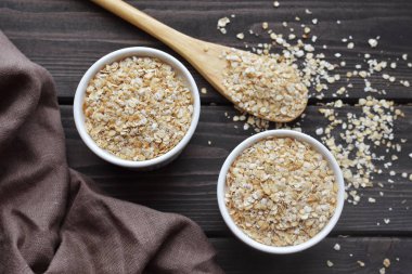 Kase ve kaşık koyu ahşap masa arka plan üzerinde yulaf, görünümü top