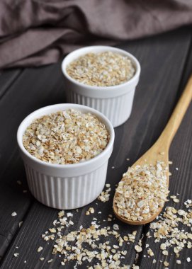 Kase ve koyu ahşap masa arka plan üzerine kaşık haddelenmiş yulaf