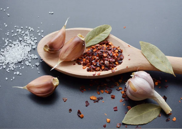 pepper, garlic, bay leaf and sea salt spices in wooden spoon