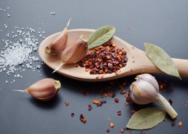 tahta kaşık içinde baharatlar tuz biber, sarımsak, defne yaprağı ve deniz