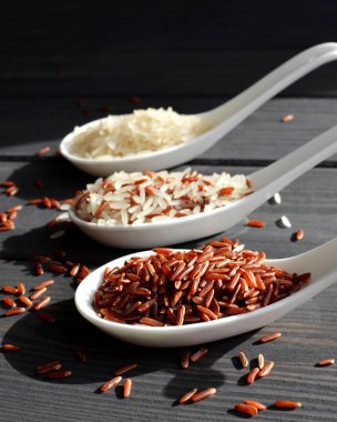 Ahşap masa arka planda kaşık pirinç farklı türleri