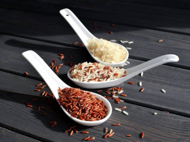 Ahşap masa arka planda kaşık pirinç farklı türleri