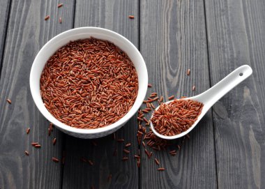 koyu ahşap arka plan karşı kaşık ile seramik bir kapta kırmızı pirinç