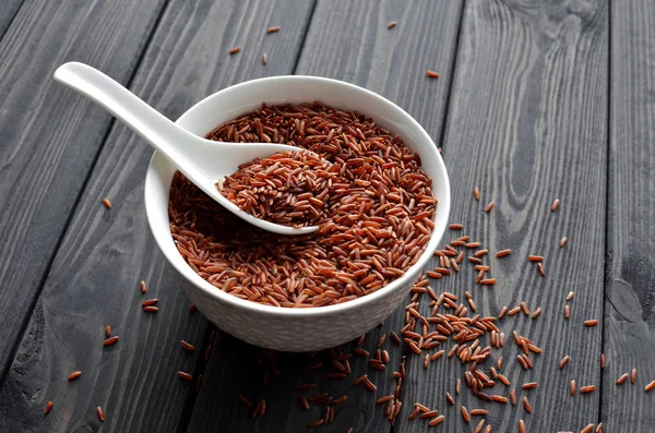 koyu ahşap arka plan karşı kaşık ile seramik bir kapta kırmızı pirinç